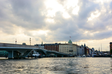 Fototapeta premium Copenhagen cityscape, Denmark. Old and modern architecture on a canal bank, panoramic view of European city, dramatic sky