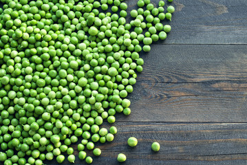 Green peas on a wooden surface, top view. Textural background