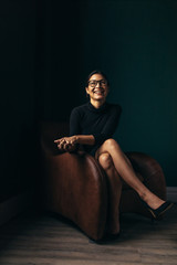 Smiling asian woman sitting relaxed on armchair