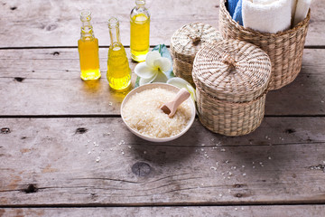 Bottles with essential aroma oil, towels, sea salt and tropical flowers plumeria  on wooden background.