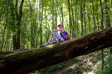 girl hiking in forest, climbing up to the log