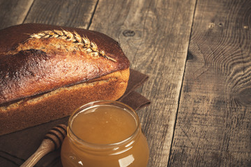 Homemade rye bread and honey glass jar on wooden table