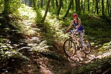 young girl in sport wear with bicycle riding in forest in summer - Powered by Adobe