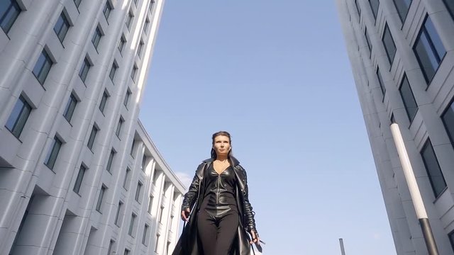 slow motion. 500 frames a second. modern slim young girl dressed in modern, eco-friendly materials. in the modern city by day. a long black cloak fading away in the wind when driving