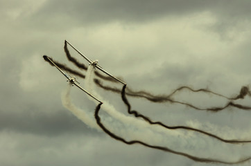 Wieczorny pokaz lotnictwa, samoloty w szyku, na niebie ślady dymu. 