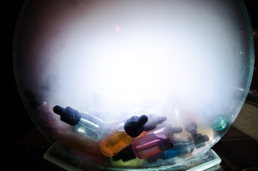 Vape concept. Smoke clouds and vape liquid bottles on dark background. Light effects. Useful as...