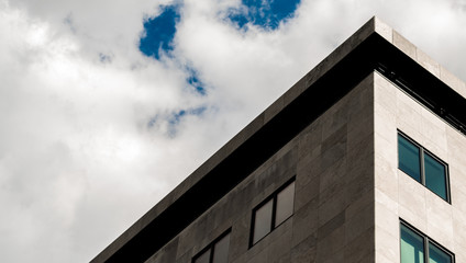 High contrast corner of a modern office building on a cloudy sunny day