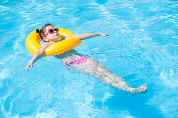 Little girl in the pool with a yellow life buoy
