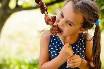 Little girl with pleasure eats shish kebab