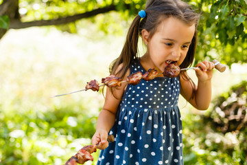 Little girl with pleasure eats shish kebab