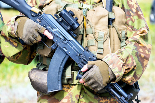Soft focus. Soldier in camouflage holding a finger on the trigger of a Kalashnikov
