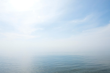 Calm tranquil blue sea with no waves and with foggy backgroudn - Powered by Adobe