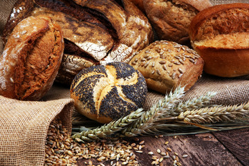 Different kinds of bread and bread rolls on wooden table