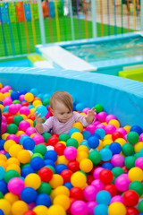 Fototapeta na wymiar Newborn baby plays in the pool with balls