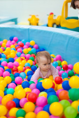 Newborn baby plays in the pool with balls