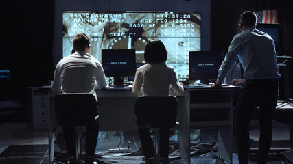 Back view of people working and managing flight in mission control center. Docking to the international space station in space. Elements of this image furnished by NASA.