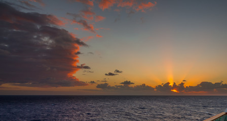 Sunset and dramatic set of clouds drifting over the tropical waters of the Caribbean Sea are lit by the last moments of daylight.