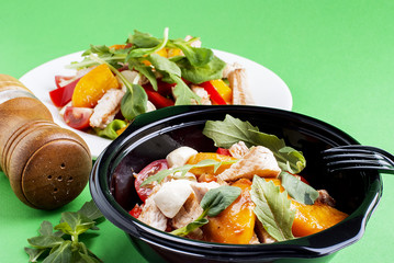 Salad with meat and peach in a plastic container