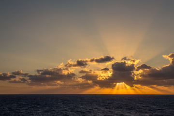 Sunset and dramatic set of clouds drifting over the tropical waters of the Caribbean Sea are lit by the last moments of daylight.