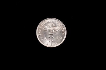 An extreme close up of an Malaysian five sen coin on a solid black background © Vitoria Holdings LLC