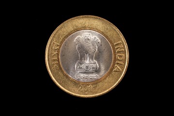 An extreme close up of an Indian ten rupee coin on a solid black background