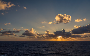 Sunset and dramatic set of clouds drifting over the tropical waters of the Caribbean Sea are lit by the last moments of daylight.