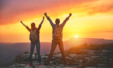 happy couple man and woman tourist at top of mountain at sunset   a hike in summer
