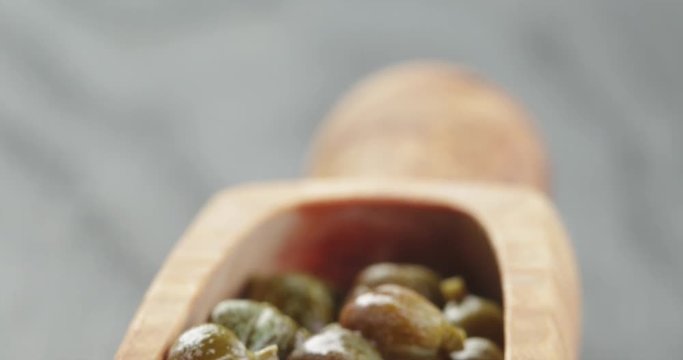 marinated capers in wood scoop on table