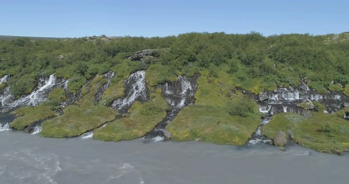 Flying close to Hraunfoss lava spring waterfall glacial river Iceland aerial 4k