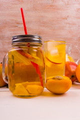Ice tea with peaches and apples on a rustic wooden background. Detox water from fresh fruit.