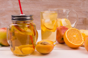 Cool lemonade with fruit on a rustic wooden background. Cold tea with peaches, oranges and apples.