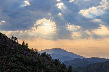 Mediterranean mountains during sunset with sun rays and pine tree silhouettes