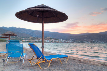 Beach with parasols at Mirabello Bay at sunset, Greece