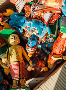Many colorful wooden toys with figure of Krishna and common people in retro traditional style of India, in box of indian store