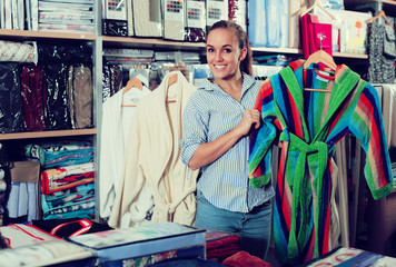 Fototapeta premium Young female customer looking through bathrobes