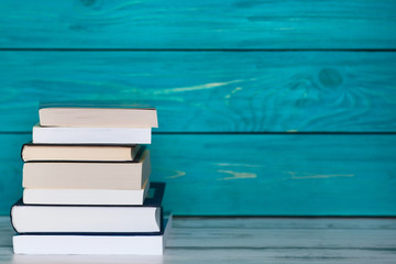 Stack of books on wooden turquoise background. Free place for text. Education concept