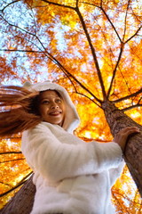 Happy young beautiful woman in autumn park on sunny day, Young woman in white coat during sunset in the park