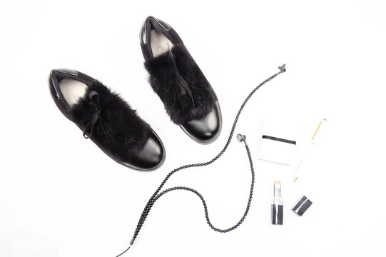Flatlay. Top view to some female items: autumn shoes, headphones, lipstick, notebook, pen. Black items on white background.