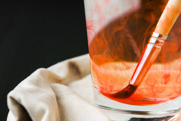 Artistic brushes soiled in paint soak in a glass with water