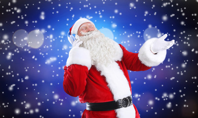 Santa Claus with headphones listening to Christmas music and snow effect on color background