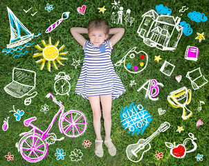 Cute little girl lying on green grass in park