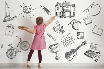 Cute little girl painting on wall in empty room