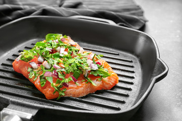 Grill frying pan with slice of salmon and herbs, closeup
