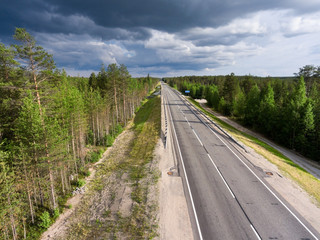 Country asphalt road among forests. Rain clouds in the sky. Summer season, Karelia, Russia