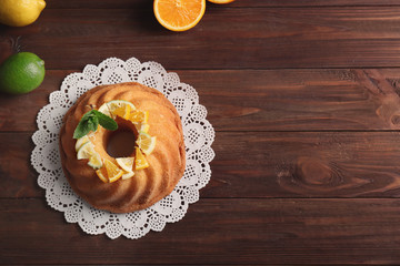 Delicious citrus cake with sliced fruits on wooden table