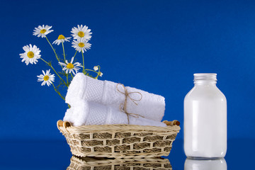 Spa. Towels are white twisted into a roll. Flowers of a camomile. Jar with cream. The background is blue