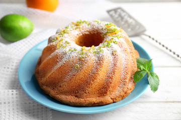 Plate with delicious citrus cake and orange zest on light table