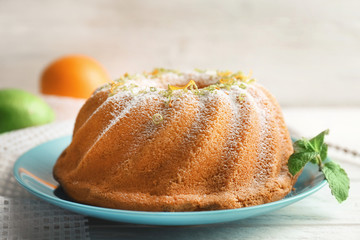 Plate with delicious citrus cake and orange zest on light table