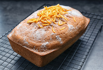 Grid with delicious citrus cake and zest on table