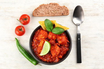 Bowl with delicious turkey chili on wooden background